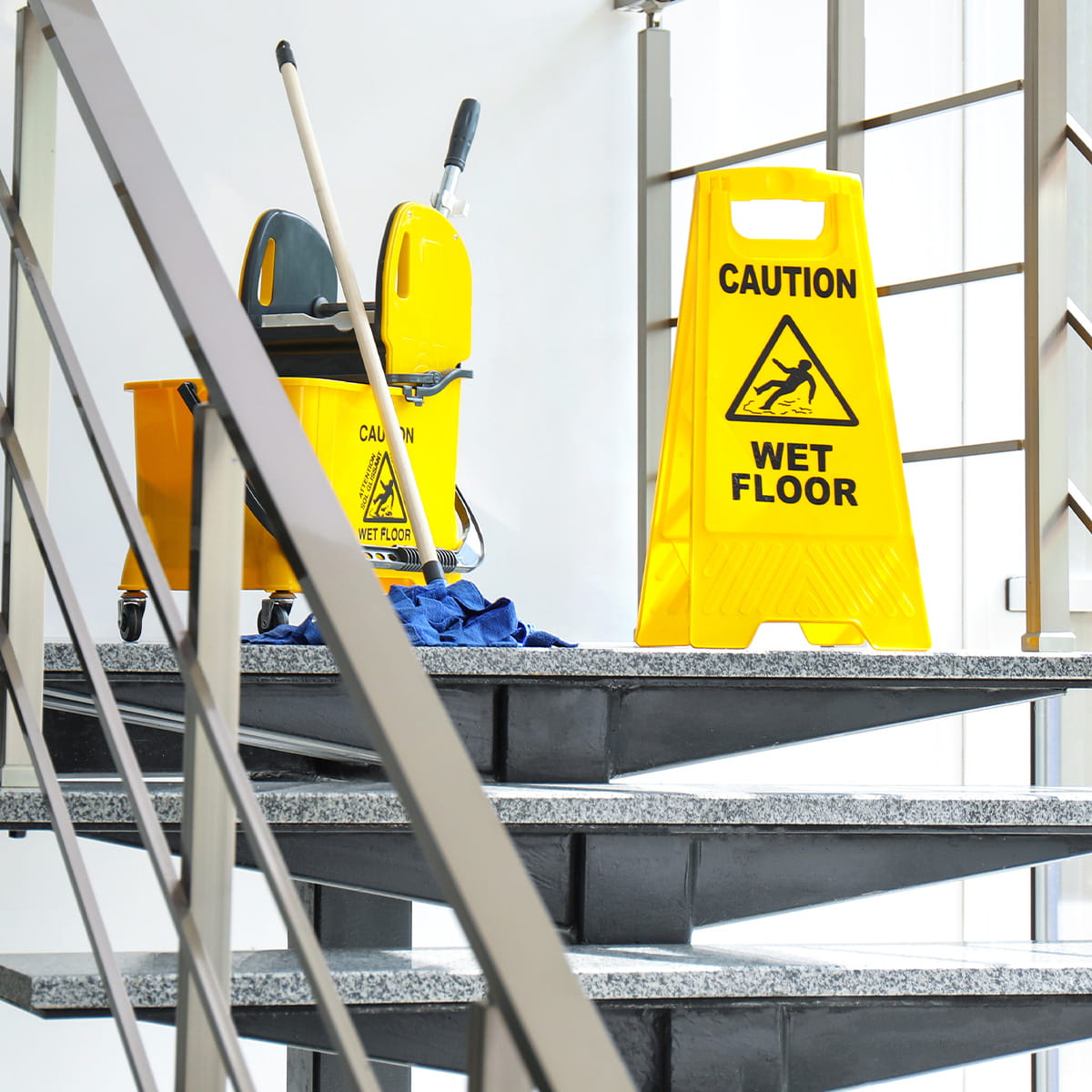 Photo of cleaning contractor's mop and bucket and wet floor sign on commercial office stairs
