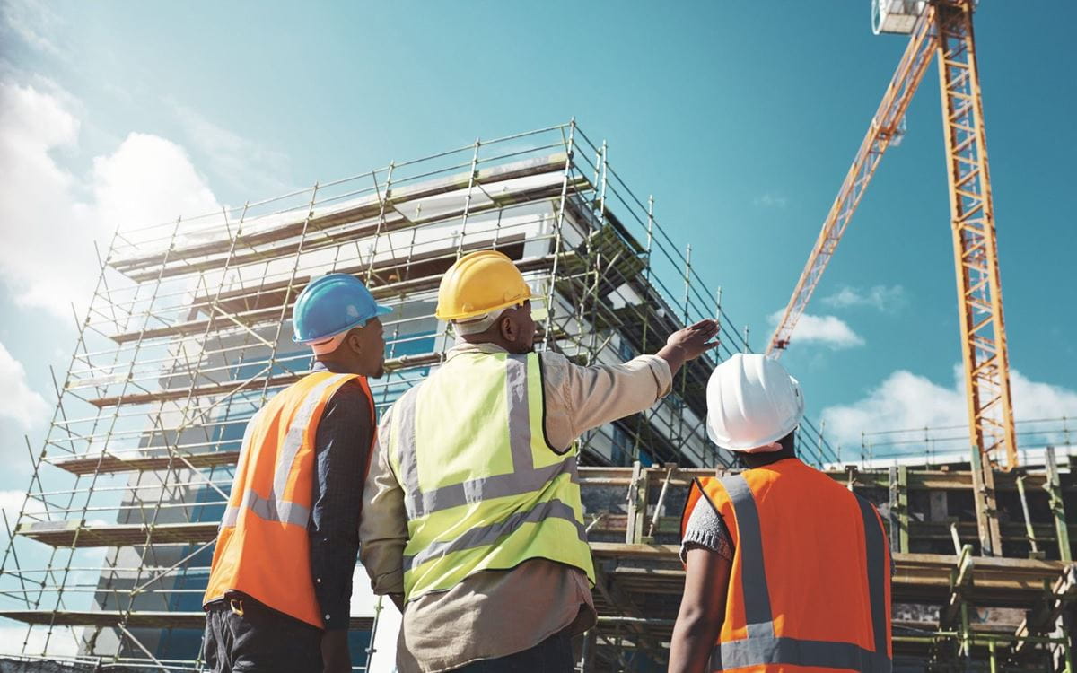Construction professionals in hard hats looking at a building under construction